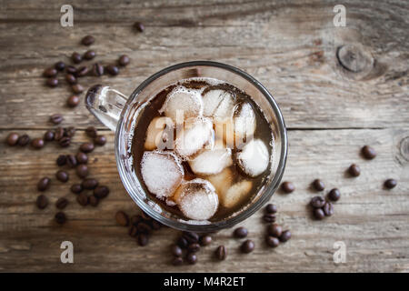 Eiskaffee und Kaffeebohnen über rustikalen Holztisch, kopieren. Iced schwarzen Kaffee für erfrischend. Stockfoto