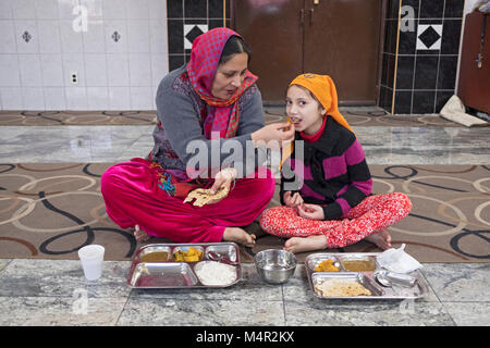 Ein indischer Sikh Frau ihre Tochter fressen in der Baba Makhan Shah Lobana Sikh Center auf 101 Avenue in Richmond Hill, Queens, New York City Stockfoto