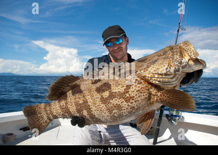 Happy fisherman Holding eine schöne Barsche fischen. Hochseefischen, big game fishing, Fang von Fischen. Stockfoto