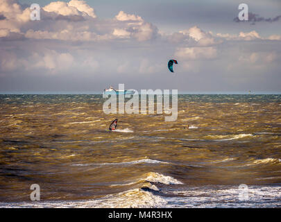 Kitesurfer, Surfer und Cargo-Schiff auf stürmischer See Stockfoto