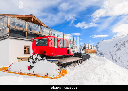 Rote Piste groomer Parkplatz vor der hölzernen Berghütte auf Piste im Skigebiet Hochgurgl-Obergurgl auf schönen sonnigen Tag, Tirol, Österreich Stockfoto