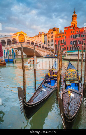 Klassische Panoramablick mit traditionellen Gondeln auf berühmten Canal Grande mit der berühmten Rialto Brücke im Hintergrund in wunderschönen goldenen Abendlicht Stockfoto