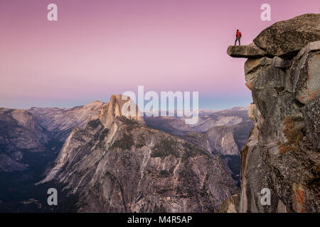 Ein furchtloser Mann Wanderer steht auf einem überhängenden Felsen am Glacier Point genießen Sie den atemberaubenden Blick auf die berühmten Half Dome im schönen Post su Stockfoto