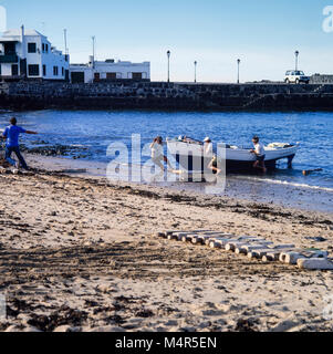 Fischer und Familie schleppen ein Boot vom Meer an den Strand auf Lanzarote, Kanarische Inseln, Spanien, Archivierung Foto Januar 1988 Stockfoto