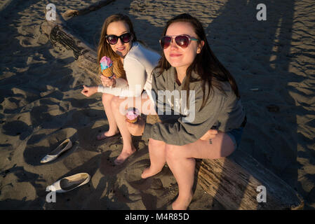 Zwei junge Frauen Eis essen am Strand. Stockfoto