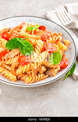 Teigwaren spirali gerührt mit gebratenen Stücke von Huhn, Kirschtomaten und Tomatensauce. Stockfoto