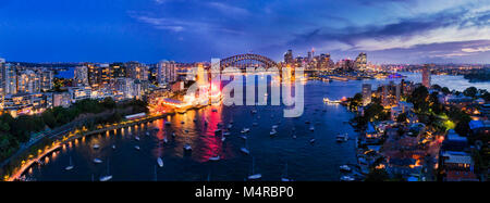 Beleuchtete Sonnenuntergang Lichter der großen Stadt Sydney landmars auf Sydney Harbour Ufer auf beiden Seiten der Sydney Harbour Bridge, wie über Wasser gesehen Stockfoto