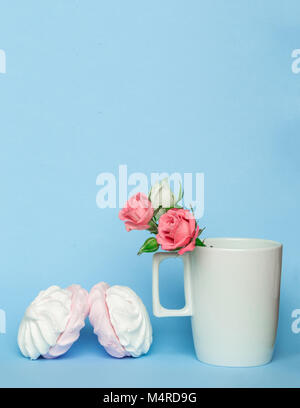 Kaffee Tasse mit Rose Blume und Zephyr Marshmallows auf blauen Pastelltönen Hintergrund. Süße Nachspeise mit Marshmallows, mit Kopie Raum Stockfoto