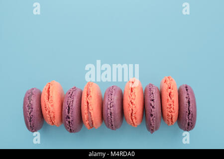 Blick von oben auf die violett und rosa Macaron auf dem blauen Pastelltönen Hintergrund. Französische dessert Macarons Stockfoto