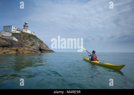 Sea kayaker unter Baily Lighthouse, Howth, County Dublin, Irland. Stockfoto