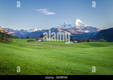 Wunderschöne Aussicht auf idyllischen alpinen Landschaft mit grünen Wiesen und schneebedeckten Gipfeln im malerischen letzten Abendlicht in der Dämmerung im Frühjahr Stockfoto