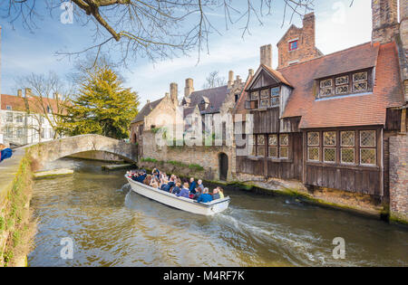 Das historische Zentrum von Brügge mit Touristen, eine Bootsfahrt entlang der traditionellen Häuser an einem schönen sonnigen Tag mit blauen Himmel, Flandern, Belgien Stockfoto