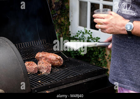 Mann Vorbereitung einer brasilianischen Grill bbq Holzkohle mit drei Stücke von Fleisch Stockfoto