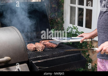 Mann Vorbereitung einer brasilianischen Grill bbq Holzkohle mit drei Stücke von Fleisch Stockfoto