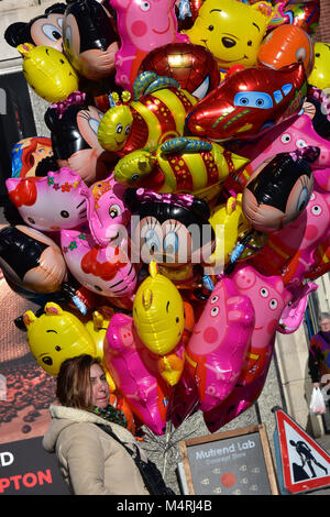 Eine Dame oder Frau femail Verkauf von Helium gefüllt Spielwaren der Kinder Luftballons in der Innenstadt Einkaufen sind einer Stadt. bunten Ballons zum Verkauf von Verkäufer. Stockfoto