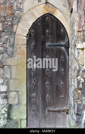 Eine alte historische hölzerne Burg oder Dungeon Tür in eine Mauer aus dickem Holz oder Eiche mit schweren sperren und Scharniere. Schloss halten Sie Türen Festungen. Stockfoto