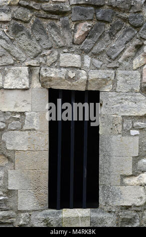 Ein gittertor in einem alten mittelalterlichen Steinmauer. Tor oder die Tür zu einem Dungeon oder Gefängniszelle mit Bars für die Sicherheit. Burg oder Festung Eingang historischen. Stockfoto