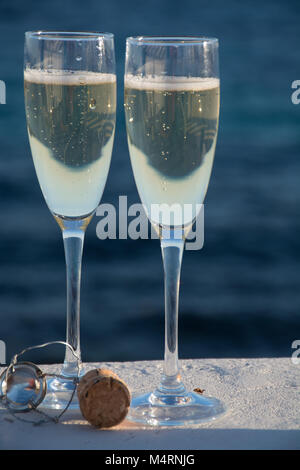 Zwei Gläser mit Champagner oder Cava Sekt serviert auf der Terrasse mit Rosa exotische Blumen, Luxus Resort mit Meerblick, romantischen Urlaub Stockfoto