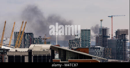 London, Großbritannien. 18 Feb, 2018. London Brand: Schwarzer Rauch steigt über Gebäude aus East London mit Emirates Airline Seilbahnen im Blick. Credit: Guy Corbishley/Alamy leben Nachrichten Stockfoto