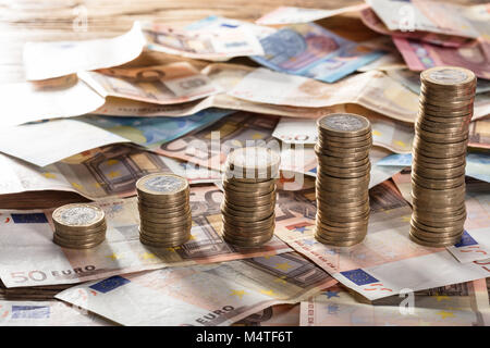 Zunehmende Münze gestapelt auf Euro-banknoten über die hölzerne Tabelle Stockfoto