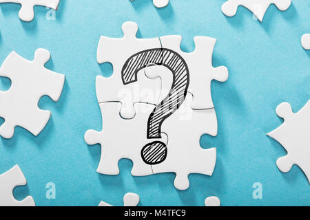 Ansicht von Fragezeichen Symbol auf weißem Puzzle über den blauen Hintergrund Stockfoto