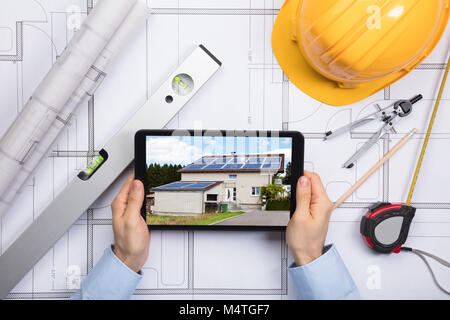 Ein männlicher Architekt mit digitalen Tablette auf Blaupause mit Arbeitsmittel im Büro Stockfoto