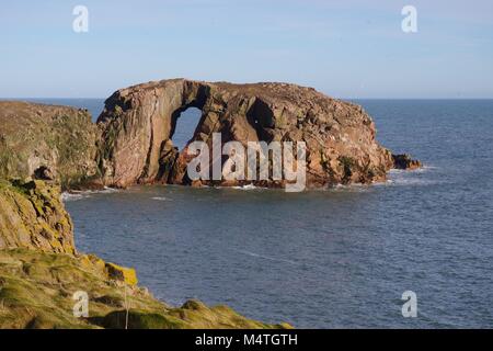 Der Bogen des Dunbuy, natürliche Meer Bogen durch eine rosa Granit Insel entlang der rauen Nordsee Klippen von Buchan, Cruden Bay, Aberdeenshire, Schottland, Großbritannien Stockfoto