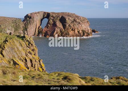 Der Bogen des Dunbuy, natürliche Meer Bogen durch eine rosa Granit Insel entlang der rauen Nordsee Klippen von Buchan, Cruden Bay, Aberdeenshire, Schottland, Großbritannien Stockfoto