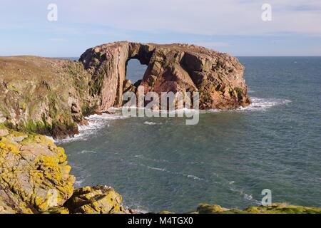 Der Bogen des Dunbuy, natürliche Meer Bogen durch eine rosa Granit Insel entlang der rauen Nordsee Klippen von Buchan, Cruden Bay, Aberdeenshire, Schottland, Großbritannien Stockfoto