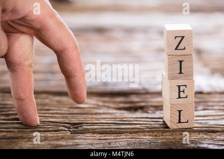 Nahaufnahme von einer Person Finger und gestapelten Ziel (Ziel in Deutsch) Wort aus Holzklötzen Stockfoto