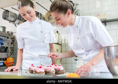 Zwei Bäcker Frauen in Backwaren Bäckerei auf Muffins arbeiten Stockfoto