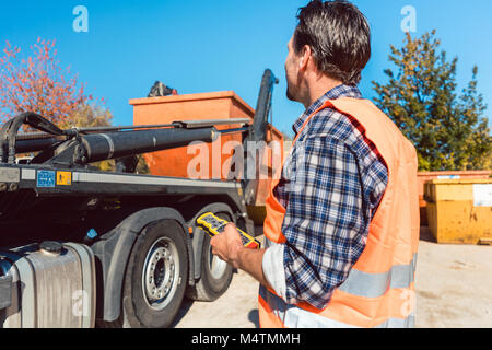 Arbeiter auf der Baustelle entladen Container für Abfälle aus Lkw Stockfoto