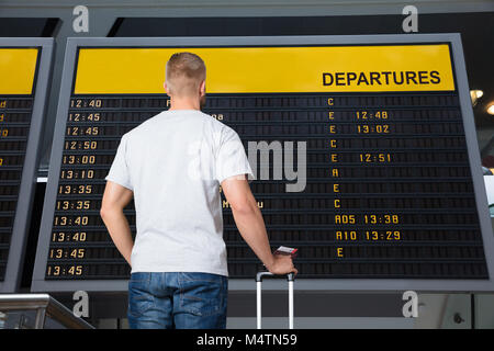 Rückansicht eines männlichen Reisenden stand Vor der Flugstatus Board am Flughafen Stockfoto