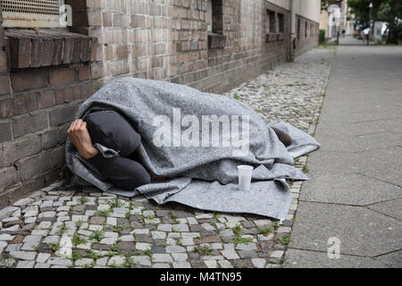 Obdachloser bedeckt mit Decke schlafen auf der Straße in der Stadt Stockfoto