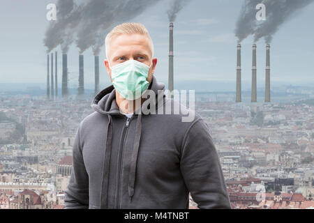 Nahaufnahme von einem Mann, der Mund Maske gegen Rauch ausstoßen von Fabrikschornsteinen Stockfoto