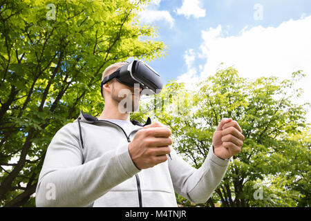 Attraktive bärtiger Mann mit Virtual Reality Brillen in Park Stockfoto