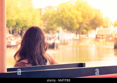 Junge Frau auf einer Bank sitzen auf der Anklagebank der Bucht bei Sonnenuntergang, Rotterdam, Niederlande Stockfoto