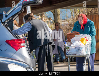 Männliche Waitrose Supermarkt Mitarbeiter und helfen, eine alte/ältere Frau mit ihrem Shopping auf der Rückseite in Ihr Auto, am Ruislip Zweig, England, UK. Stockfoto