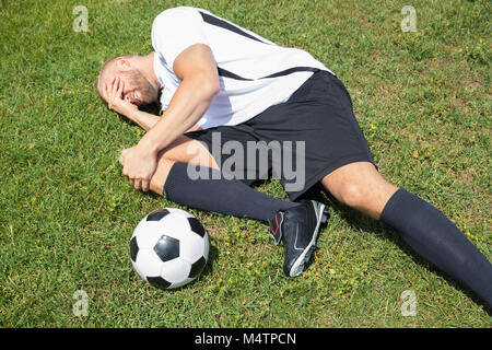 Nahaufnahme der männlichen Fußball-Spieler Leiden Knieverletzung liegen auf Feld Stockfoto