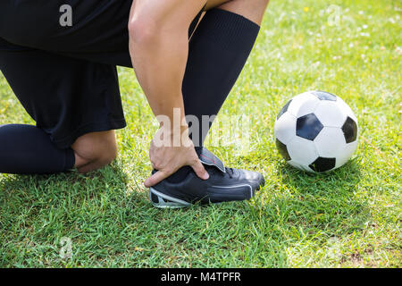Nahaufnahme der männlichen Fußball-Spieler Leiden Knöchelverletzung auf Feld Stockfoto