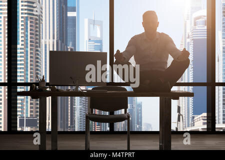 Junge kaukasier Geschäftsmann auf dem Tisch Meditieren im Büro Stockfoto