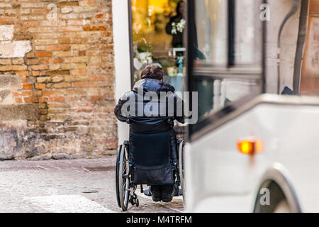 Behinderten Jungen auf Rollstuhl Pässe auf Fußgänger Streifen vor einem Bus Stockfoto