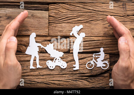 Nahaufnahmen der Hände zum Schutz der Familie weiss Papier schneiden Sie auf hölzernen Tisch Stockfoto