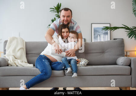 Bild der glücklichen Familie mit Sohn auf grau Sofa Stockfoto