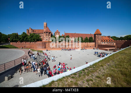 Gruppen von Menschen für Sightseeing Tour auf einem Platz vor der Malbork in Polen, in Europa warten Stockfoto