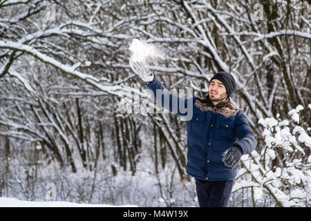 Glückliche junge Mann mit Bart werfen Schneeball Stockfoto