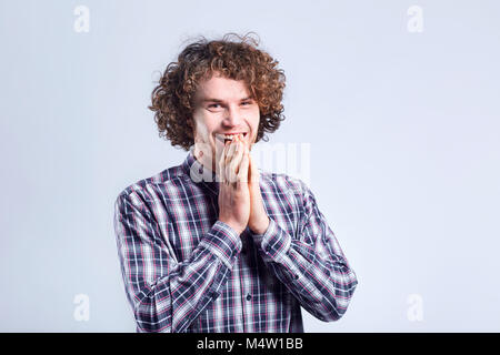 Curly-haired Kerl überrascht freut sich mit einem positiven Gefühl. Stockfoto