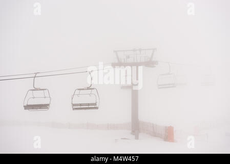 Leere Sessellift an einem Tag von Blizzard und Nebel in der Sierra de Béjar Ski Resort - La Covatilla, Salamanca, Spanien. Stockfoto