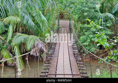 Wackelige hölzerne Brücke über einen Fluss in der Drake Bay auf der Halbinsel Osa im Süden von Costa Rica. Stockfoto