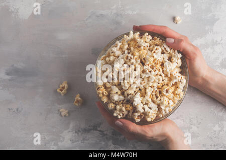 Golden caramel Popcorn in Glasschale in Händen, Ansicht von oben, kopieren. Stockfoto